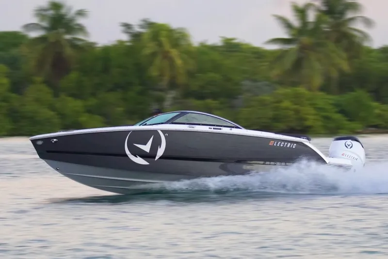 Slide: The Image of Manufacturer Provided Image: 2024 Four Winns H2e electric boat speeding on water with lush greenery in the background. - 13