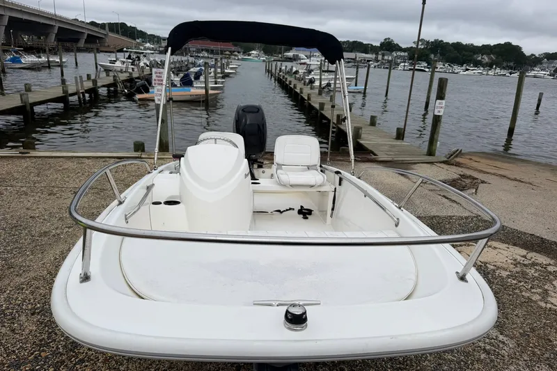 Slide: The Image of 2017 Boston Whaler 130 Super Sport boat docked at a marina with overcast skies. - 2