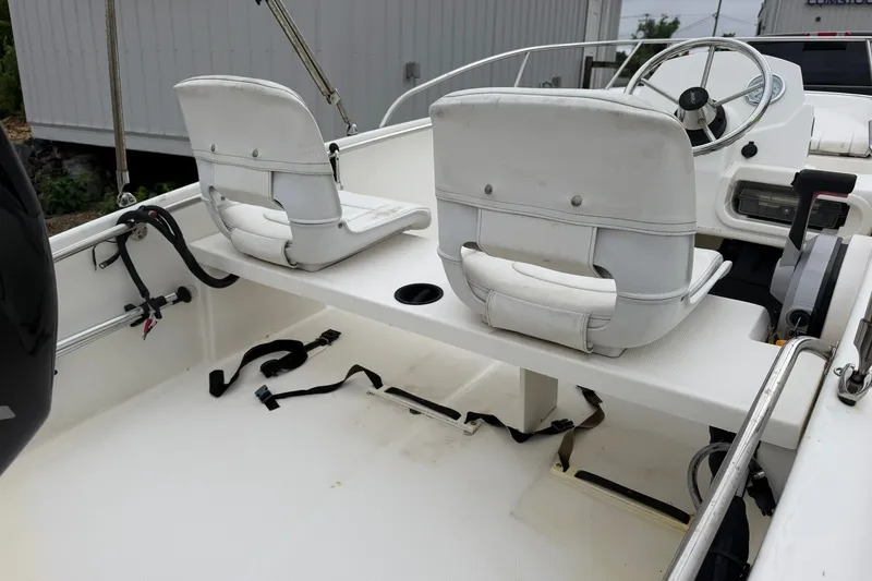 Slide: The Image of 2017 Boston Whaler 130 Super Sport boat interior with white seating and steering console. - 7