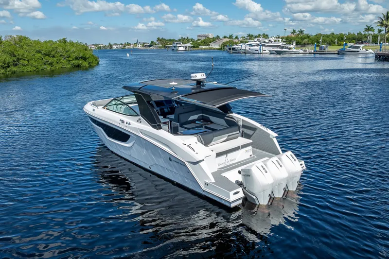 Slide: The Image of 2022 Cruisers Yachts 38 GLS OB on serene water, showcasing sleek design and triple outboard engines. - 1