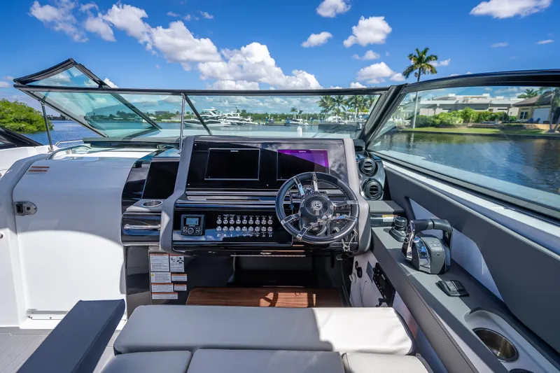 Slide: The Image of 2022 Cruisers Yachts 38 GLS OB helm with modern controls and scenic waterway view. - 19