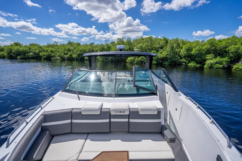 Slide: The Image of 2022 Cruisers Yachts 38 GLS OB on serene water, lush greenery, and blue sky backdrop. - 11