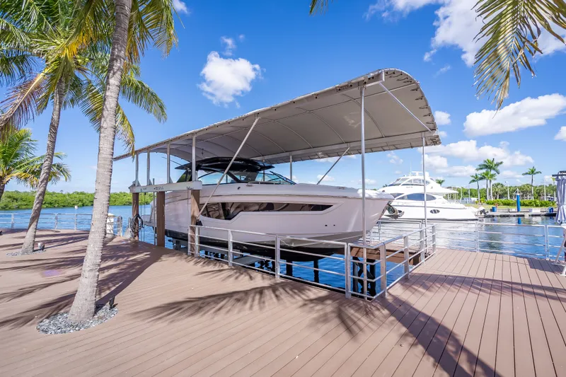 The Image of 2022 Cruisers Yachts 38 GLS OB docked under canopy, surrounded by palm trees and water. - 0