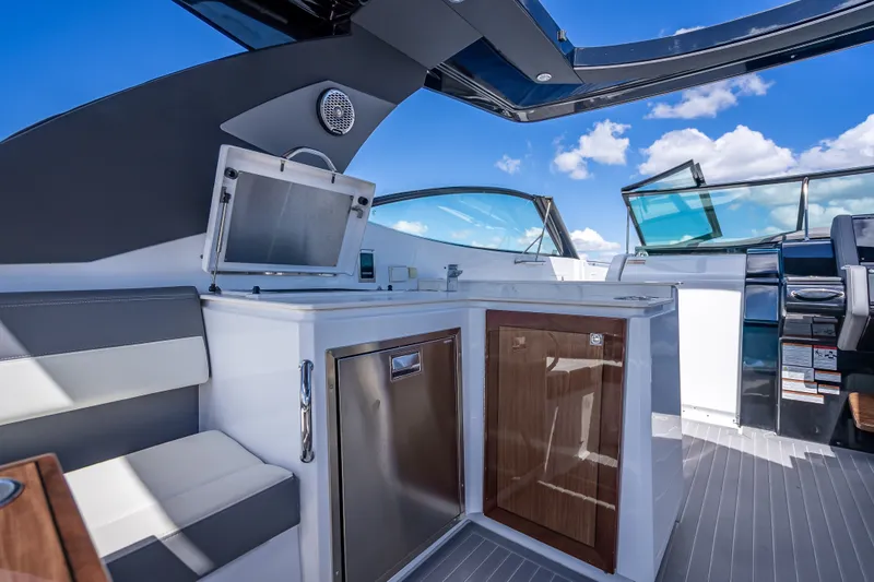 Slide: The Image of 2022 Cruisers Yachts 38 GLS OB interior with seating and kitchenette under blue sky. - 33