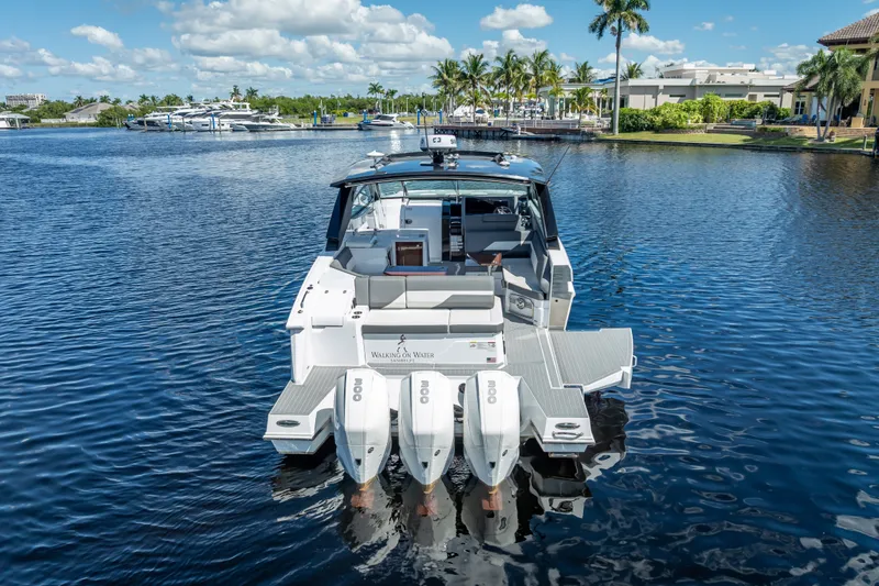 Slide: The Image of 2022 Cruisers Yachts 38 GLS OB on serene water with palm trees in background. - 9