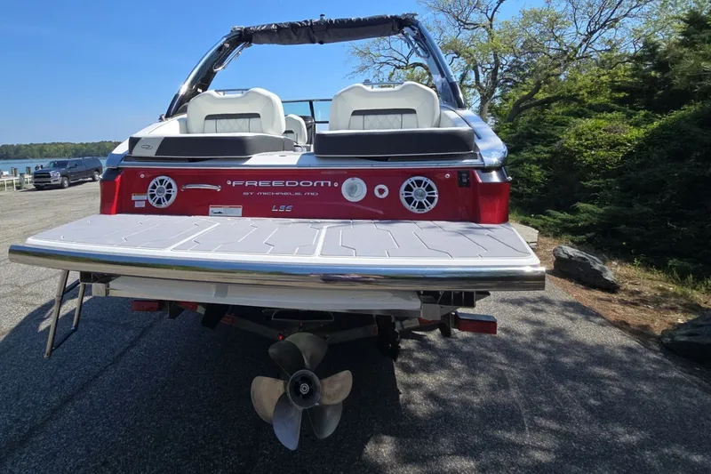 Slide: The Image of 2022 Regal LS6 boat with red exterior, parked near a scenic lakeside. - 4