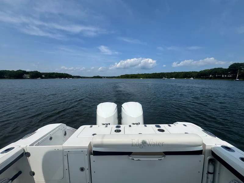 Slide: The Image of View from the stern of an Edgewater 280CX Crossover over calm water and wooded shores. - 15