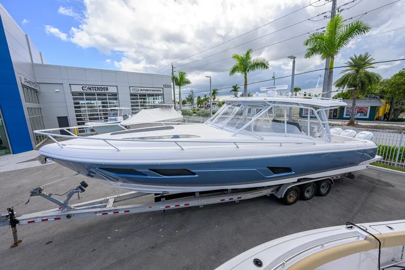 Slide: The Image of 2022 Intrepid 409 Valor boat on trailer at dealership, surrounded by palm trees. - 1