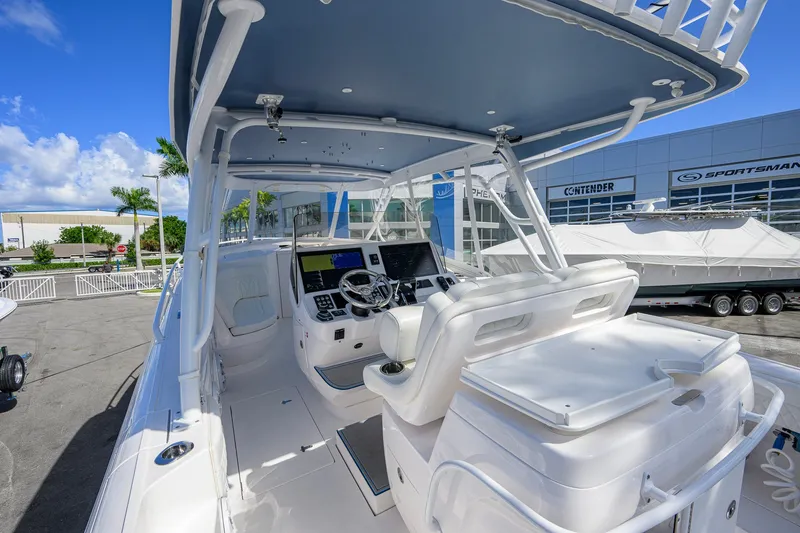 Slide: The Image of 2022 Intrepid 409 Valor boat cockpit with modern controls and seating, docked outdoors. - 14