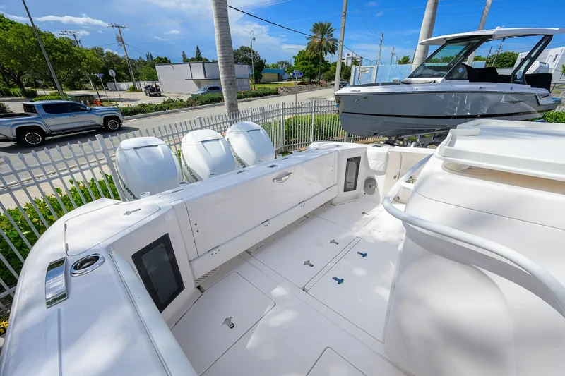 Slide: The Image of 2022 Intrepid 409 Valor boat with triple outboard engines, docked near a road. - 31