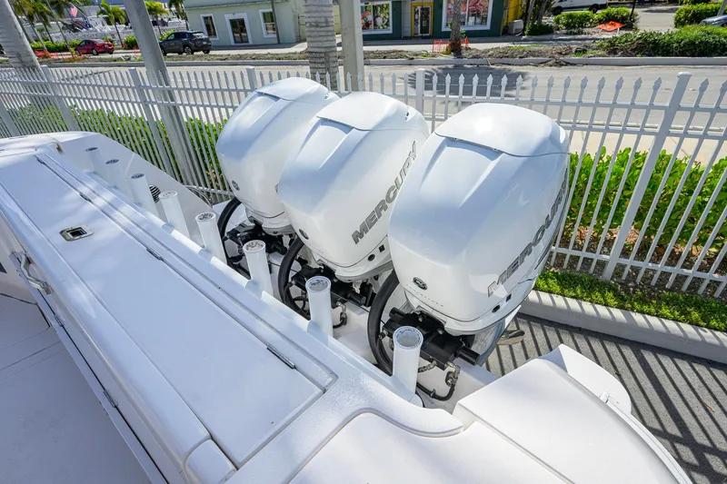 Slide: The Image of Triple Mercury outboard engines on a 2022 Intrepid 409 Valor boat, docked near a fence. - 53