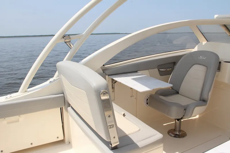 Slide: The Image of 2022 Scout 240 Dorado boat interior with seating and table on calm water. - 10