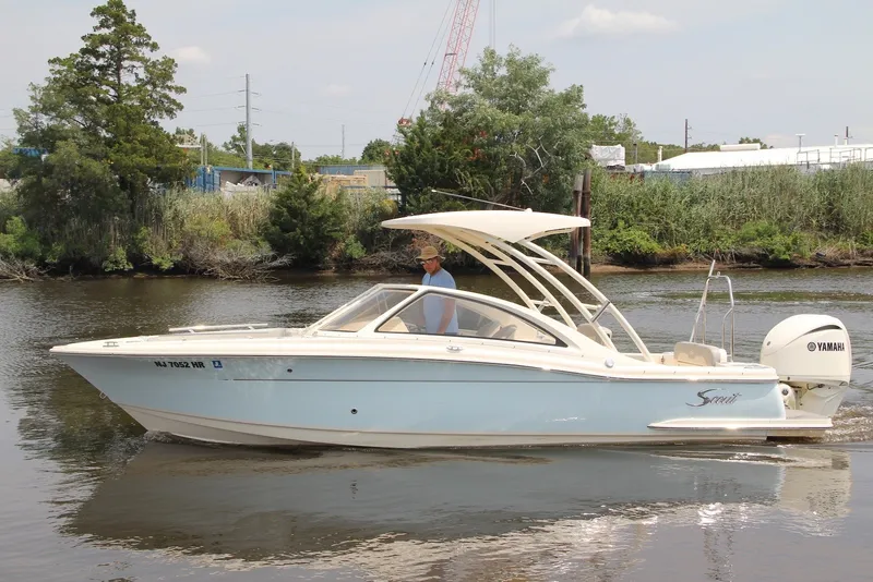 Slide: The Image of 2022 Scout 240 Dorado boat cruising on a calm river with lush greenery. - 2