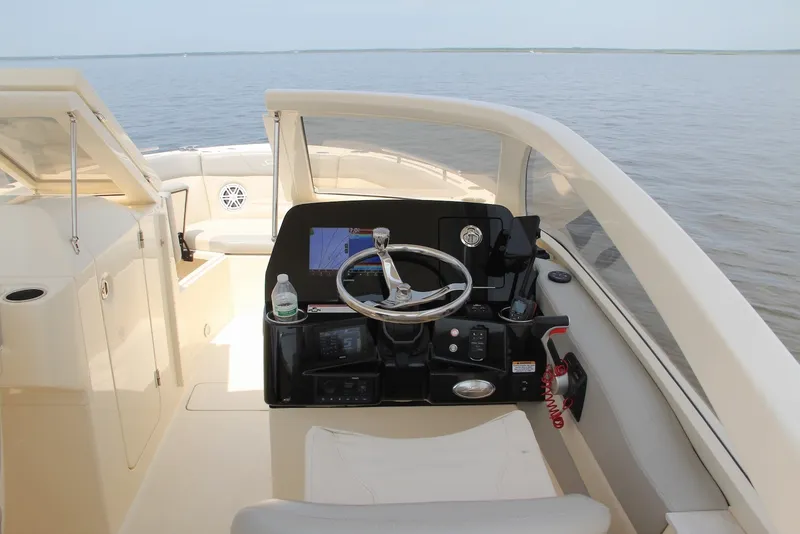 Slide: The Image of 2022 Scout 240 Dorado boat helm with steering wheel and navigation system on calm water. - 9