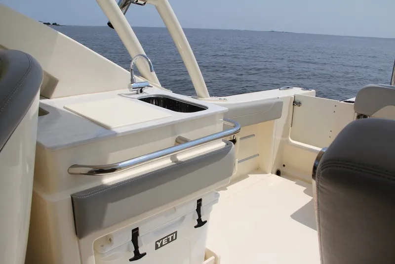 Slide: The Image of 2022 Scout 240 Dorado boat interior with sink and Yeti cooler, overlooking the ocean. - 14