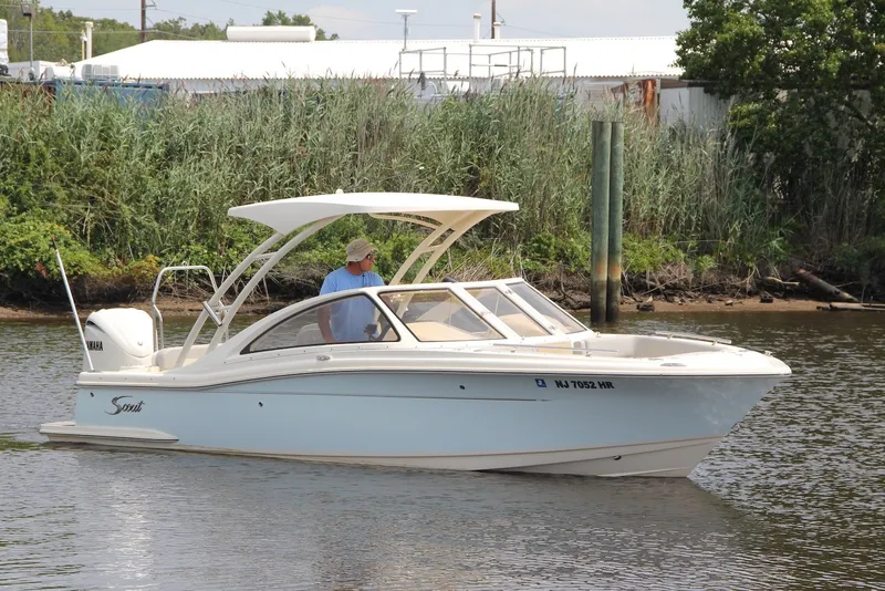 Slide: The Image of 2022 Scout 240 Dorado boat cruising on a calm river near lush greenery. - 1