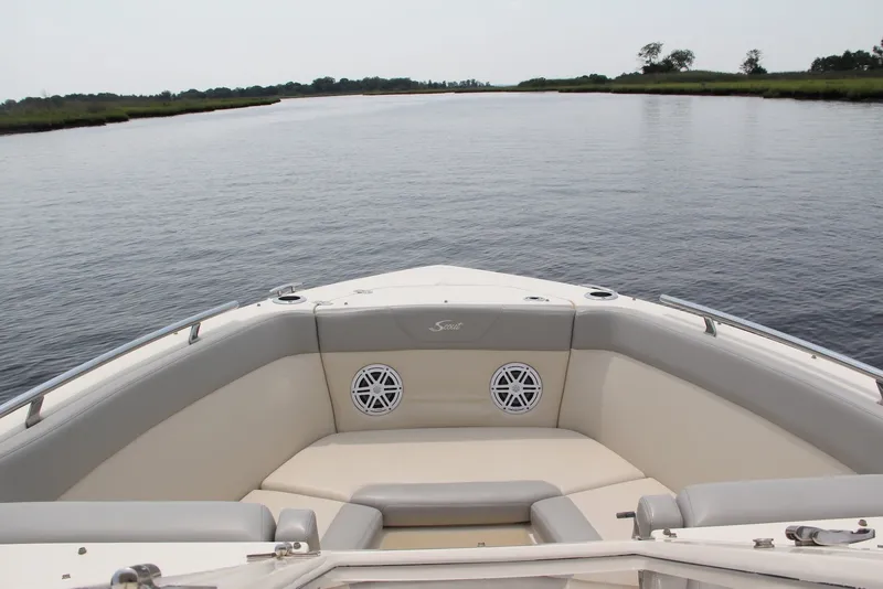 Slide: The Image of 2022 Scout 240 Dorado boat interior with cushioned seating on calm water. - 8