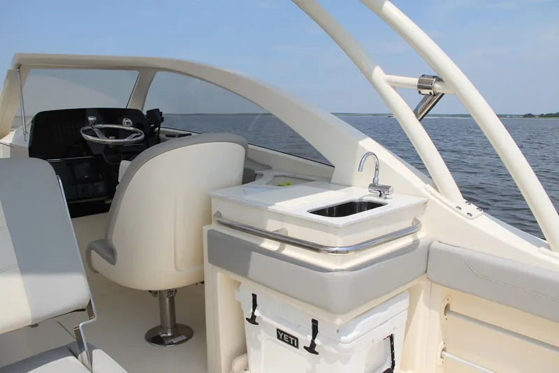 Slide: The Image of 2022 Scout 240 Dorado boat interior with steering wheel and sink, on calm water. - 16