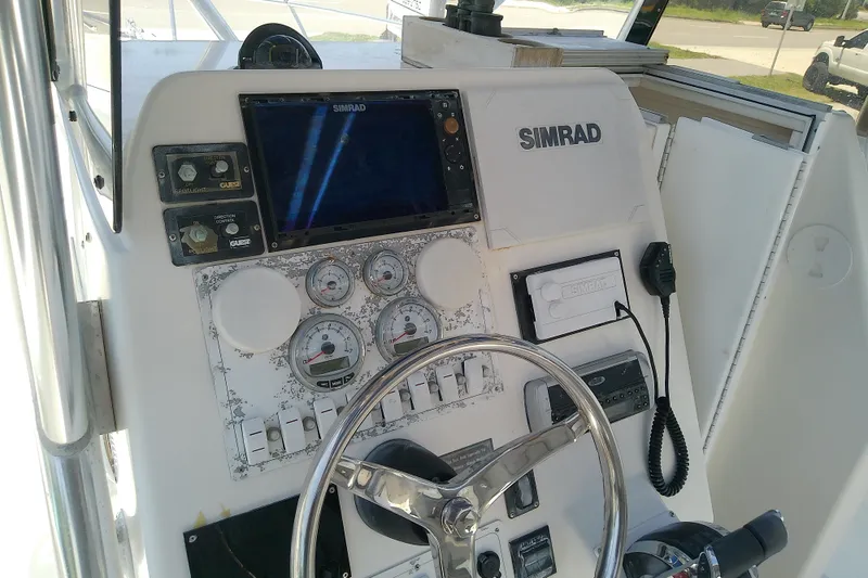 Slide: The Image of 2004 Stamas 310 Tarpon boat dashboard with Simrad navigation system and steering wheel. - 48