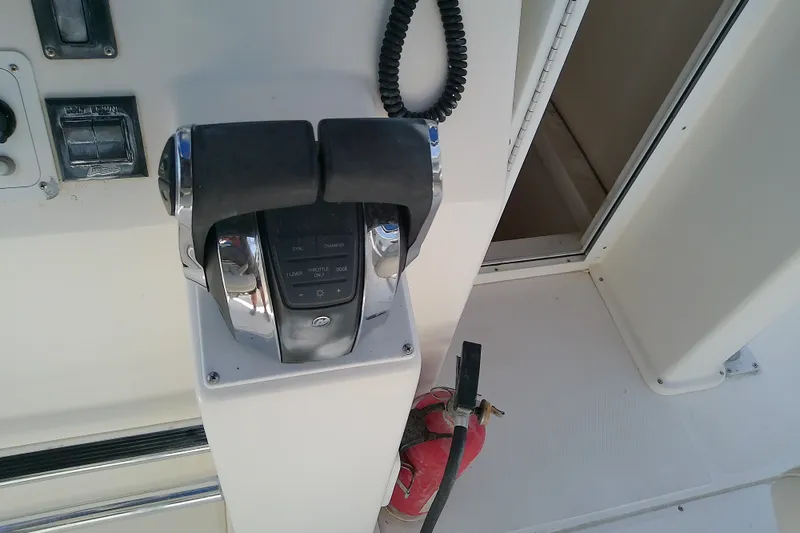 Slide: The Image of Throttle controls on a 2004 Stamas 310 Tarpon boat, with a fire extinguisher nearby. - 47