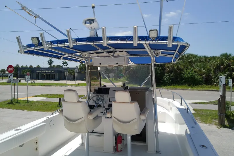 Slide: The Image of 2004 Stamas 310 Tarpon boat with blue canopy and dual seats, parked near a road. - 15