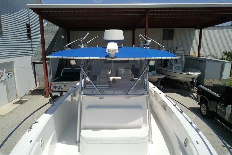 Slide: The Image of 2004 Stamas 310 Tarpon boat with blue canopy, docked in a marina. - 31