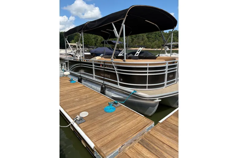 The Image of 2016 Harris Sunliner 220 pontoon boat docked with canopy under blue sky. - 0