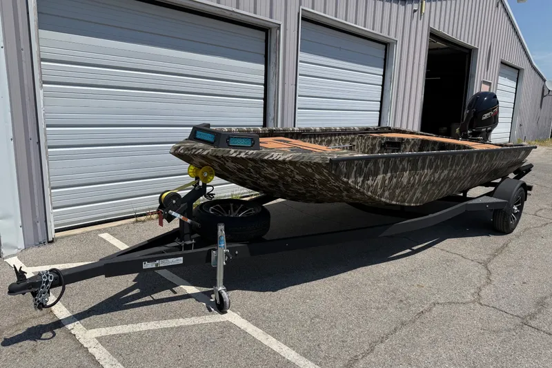 Slide: The Image of 2027 Avid 18 Commander boat on trailer, parked outside a garage with closed doors. - 4