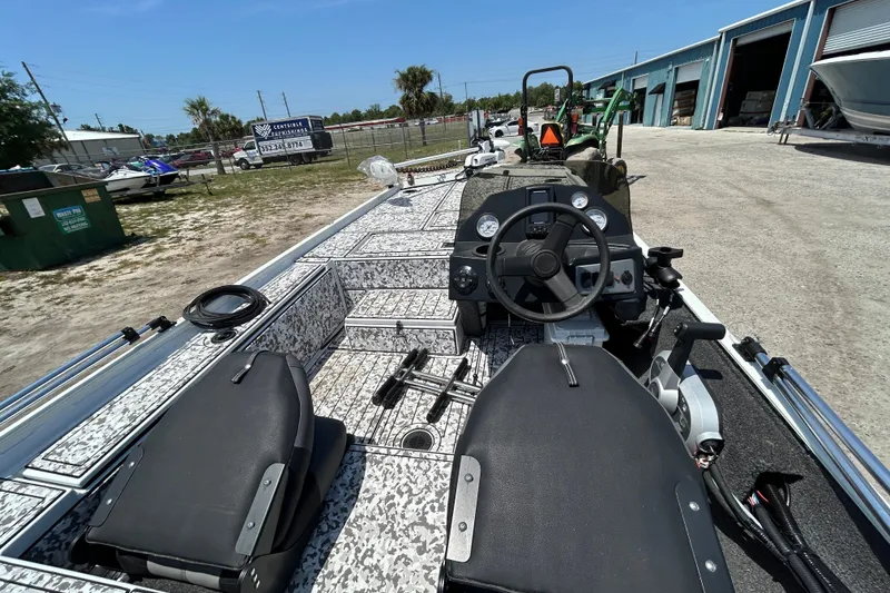 Slide: The Image of 2023 Crestliner 1600 Storm boat interior with steering wheel and seating, parked outdoors. - 6