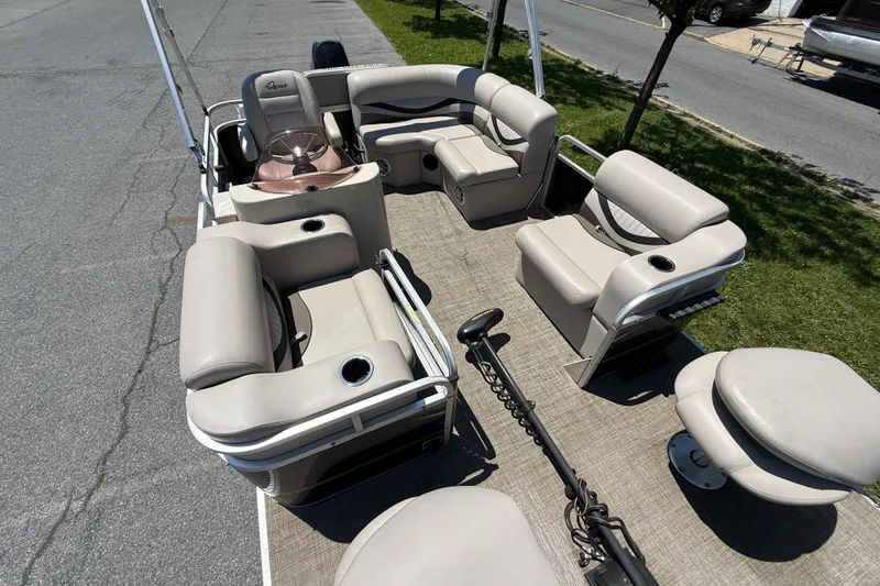 Slide: The Image of Pontoon boat interior with beige seating, Qwest 7516 SC, 2018 model, parked on pavement. - 7