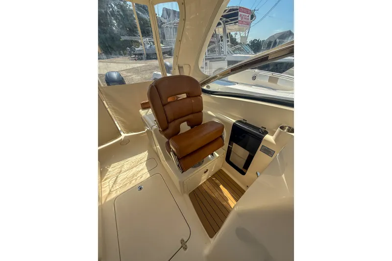 Slide: The Image of 2018 Scout 275 Dorado boat interior with brown leather seating and wooden flooring. - 25