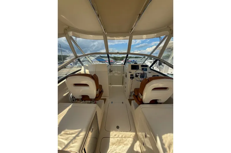 Slide: The Image of Interior view of a 2018 Scout 275 Dorado boat, featuring dual captain's chairs and a sleek dashboard. - 21