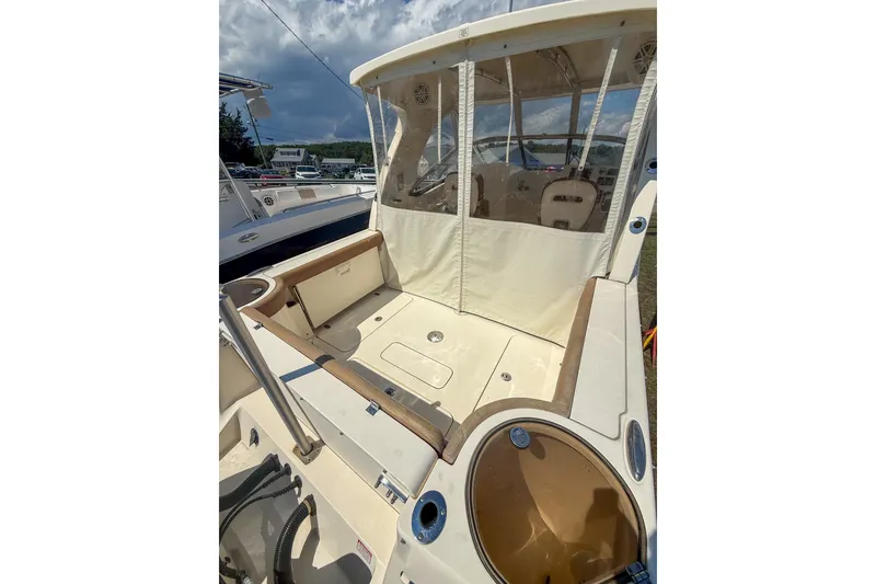 Slide: The Image of 2018 Scout 275 Dorado boat interior with seating and storage, under a cloudy sky. - 14