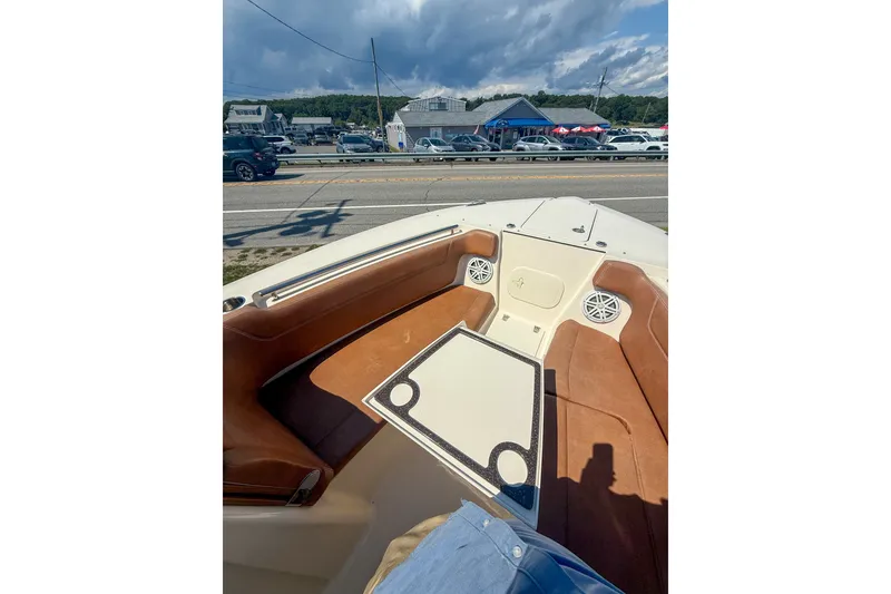 Slide: The Image of 2018 Scout 275 Dorado boat interior with brown seating and table, parked near a road. - 32
