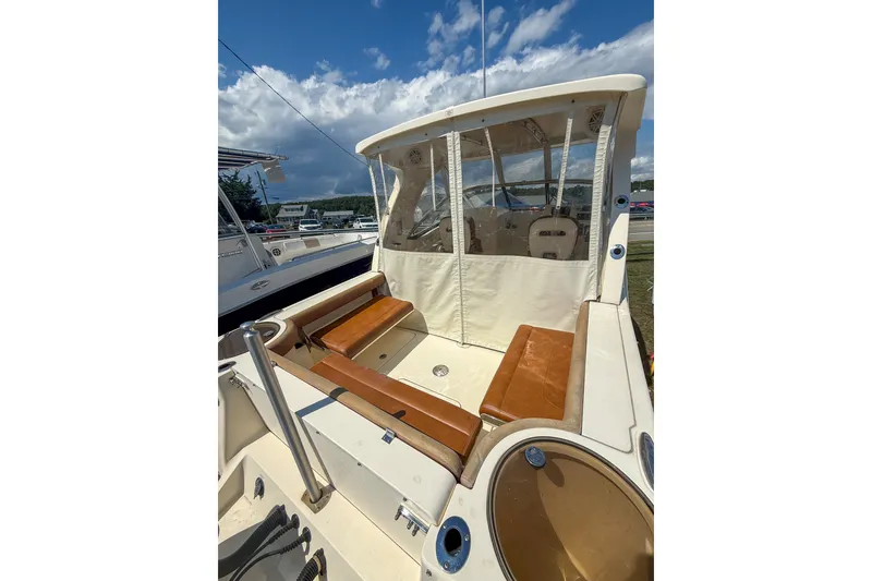 Slide: The Image of 2018 Scout 275 Dorado boat interior with tan seating and protective canopy under a blue sky. - 15
