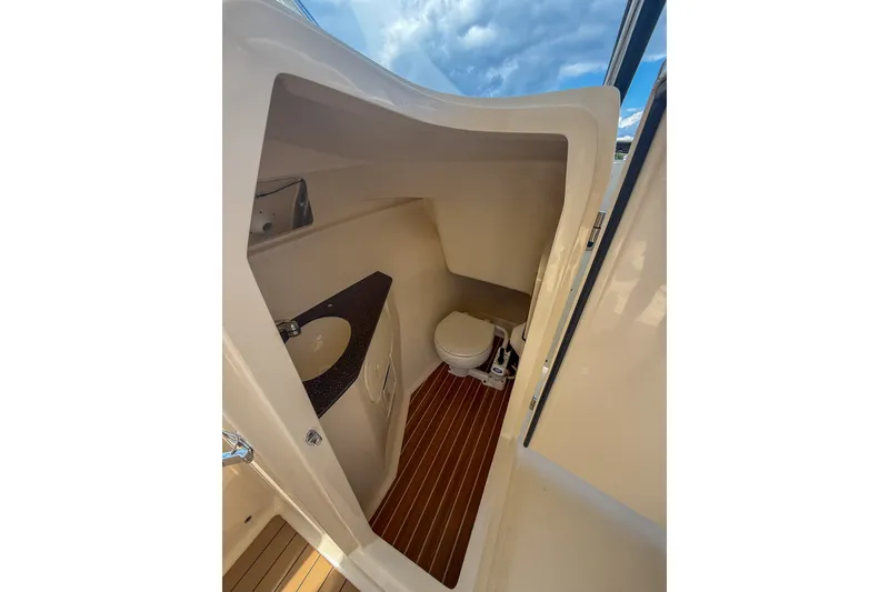 Slide: The Image of 2018 Scout 275 Dorado boat interior with compact bathroom and wooden flooring. - 29