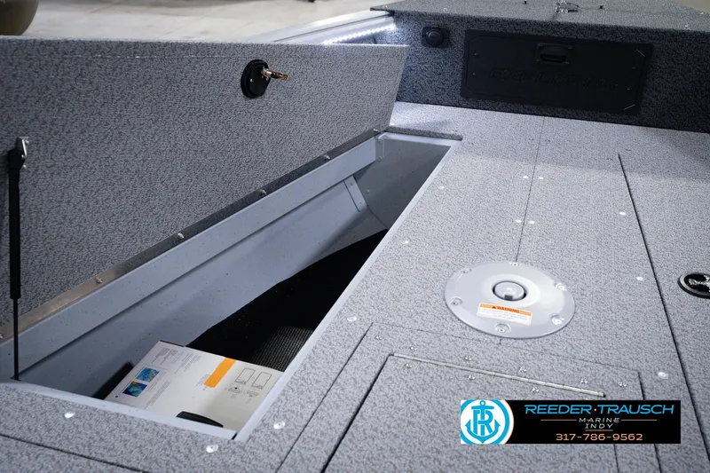 Slide: The Image of 2026 Lund 1800 Explorer SS boat storage compartment with open hatch and visible documents. - 34