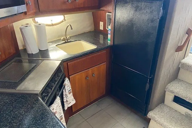 Slide: The Image of Compact kitchen in 2000 Carver 406 Aft Cabin Motor Yacht with sink, stove, and fridge. - 26