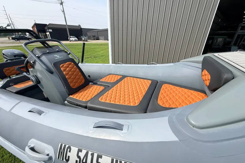 Slide: The Image of 2023 Highfield Sport 420 boat with orange quilted seats, docked near a metal building. - 9