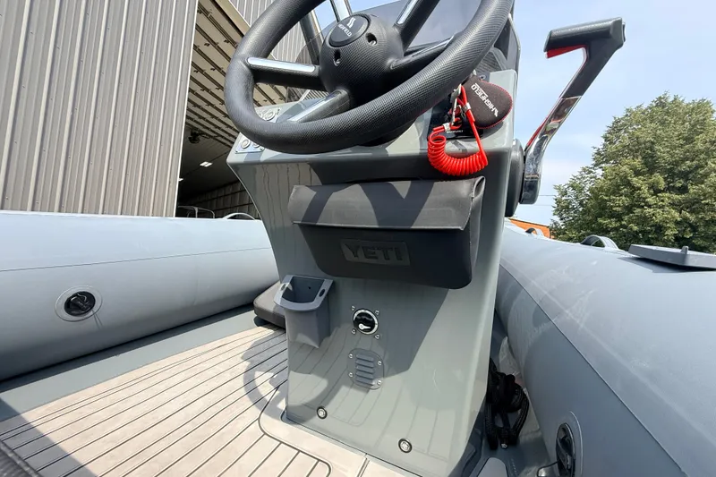 Slide: The Image of 2023 Highfield Sport 420 boat console with steering wheel and throttle, docked near a building. - 16