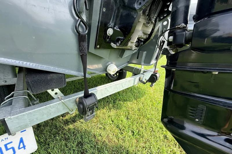 Slide: The Image of 2023 Highfield Sport 420 boat trailer detail on grass, showcasing engine and securing straps. - 13