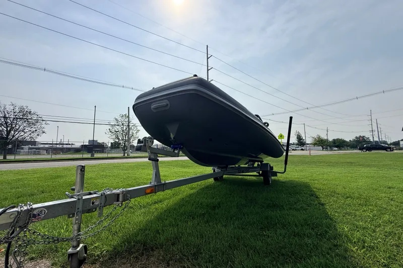 Slide: The Image of 2023 Highfield Sport 420 boat on trailer, parked on grass under a sunny sky. - 14