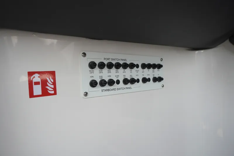 Slide: The Image of Control panel on 2027 Chaparral 270 OSX boat, featuring various switches and fire extinguisher sign. - 60