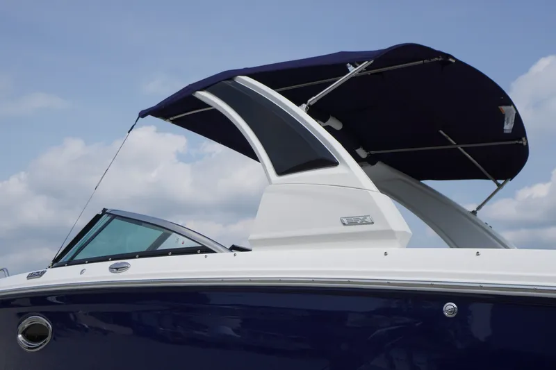 Slide: The Image of 2027 Chaparral 270 OSX boat with sleek design and canopy against a cloudy sky. - 2