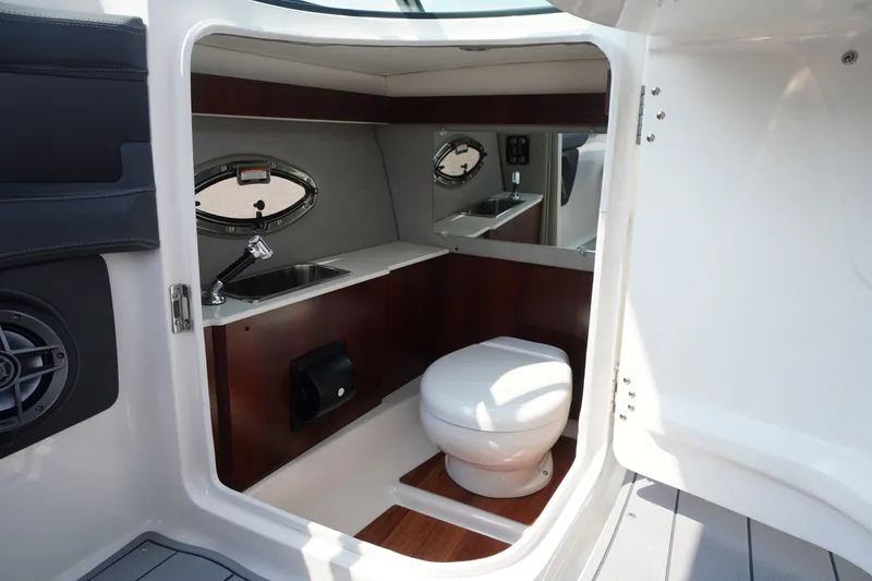 Slide: The Image of Interior of 2027 Chaparral 270 OSX boat featuring a compact bathroom with sink and toilet. - 23