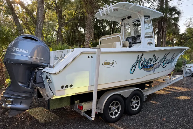 Slide: The Image of 2018 Sea Hunt Gamefish 27 boat on trailer with Yamaha engine in wooded area. - 15