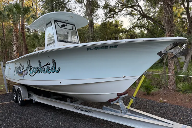 Slide: The Image of 2018 Sea Hunt Gamefish 27 boat on trailer, surrounded by trees. - 55