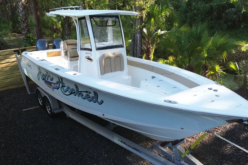 Slide: The Image of 2018 Sea Hunt Gamefish 27 boat on trailer, surrounded by lush greenery. - 6