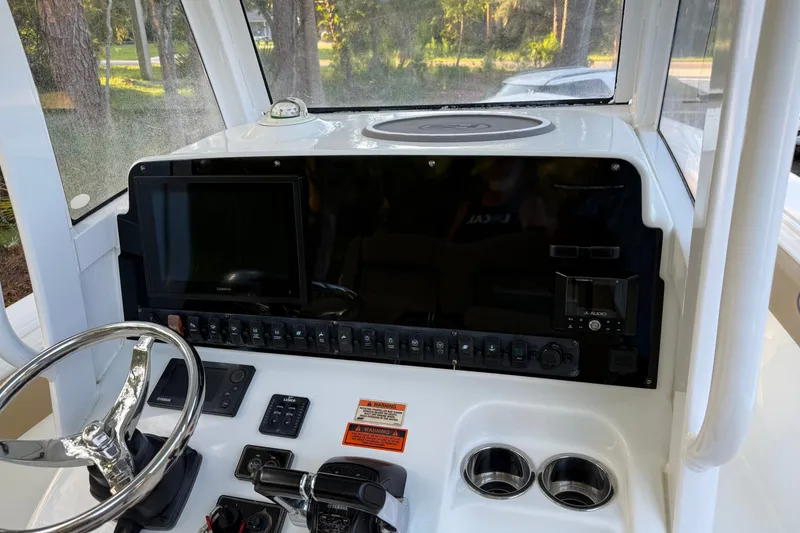 Slide: The Image of 2018 Sea Hunt Gamefish 27 dashboard with steering wheel, controls, and navigation display. - 24