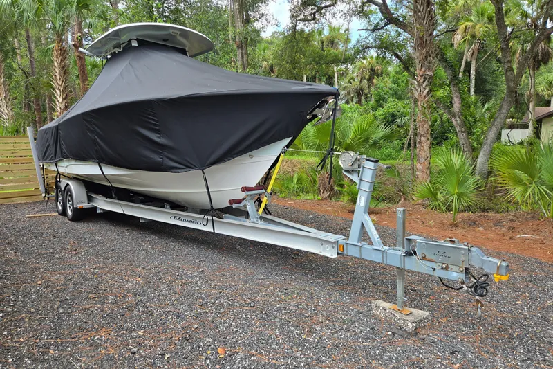 Slide: The Image of 2018 Sea Hunt Gamefish 27 boat on trailer, covered, surrounded by lush greenery. - 8